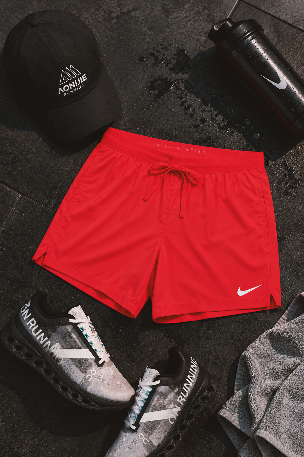 Men's running gear flat lay with red Nike shorts, black running cap and performance running shoes