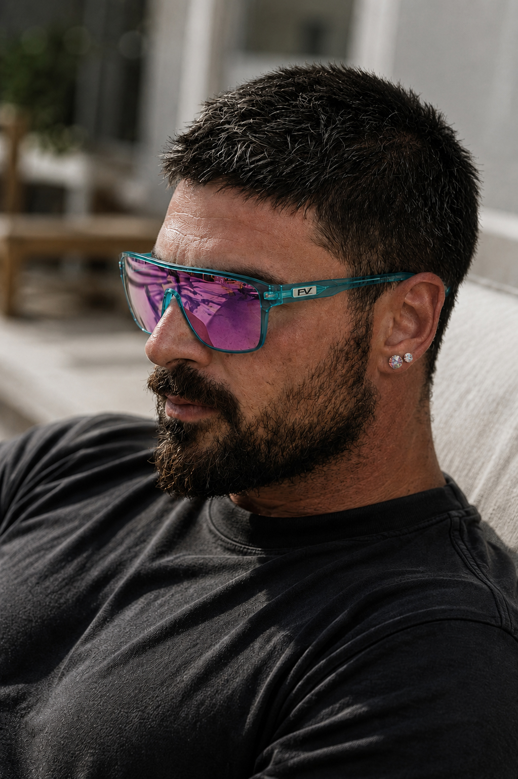Man wearing black-tone multicolor crystal stud earrings with mirrored sunglasses for a bold modern jewelry look.